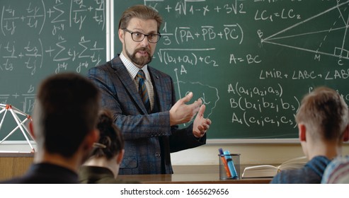 Professor In Formal Wear And Glasses Explaining New Math Subject To Group Of Students In Schoolroom