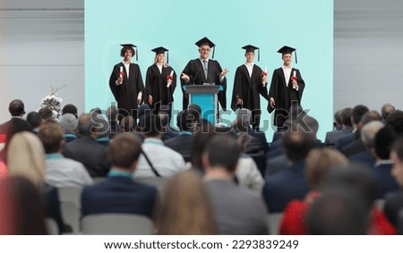 Professor and graduate students standing on a podium in front of people in the audience