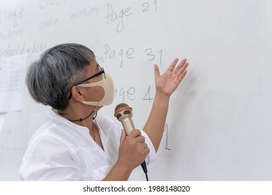 Professor Senior Asian Teaching Explain Wear Medical Face Mask For Safety Speaking Microphone At Whiteboard In Classroom In University. Speaker Or Teacher In Health Care Prevent COVID-19 Disease