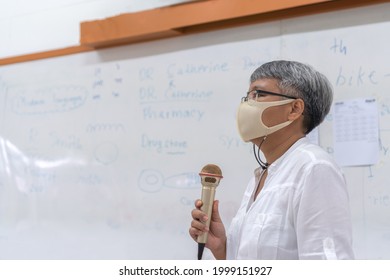 Professor Senior Asian Teaching Explain Wear Medical Face Mask For Safety Speaking Microphone At Whiteboard In Classroom In University. Speaker Or Teacher In Health Care Prevent COVID-19 Disease