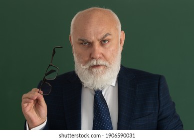 Professor Or Serious Teacher. Elderly Man Teacher On A Blank Chalkboard During Lesson, Teaching Class At College. Think Senior