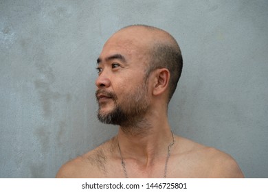 profile of 30-40s beard bald Japanese topless happy cool man portrait on grey concrete wall background 