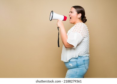 Profile Of An Angry Obese Woman Protester Screaming With A Megaphone And Asking For Justice In Front Of A Background With Copy Space