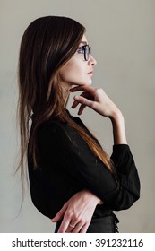 Profile Of  Attractive Young Business Woman In Glasses  In Side View Standing  Solving A Problem Staring Thoughtfully Up Into The Air With Her Finger To Her Chin. Empty  Copy Space.