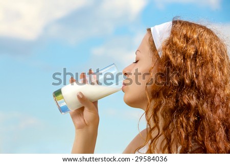 Profile of the beautiful girl drinking milk against the sky