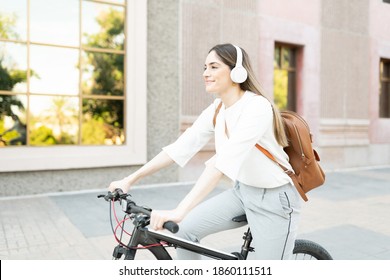 Profile Of A Caucasian Woman In Her 30s With Headphones Listening To Music While Riding A Bike In Her Commute To Work