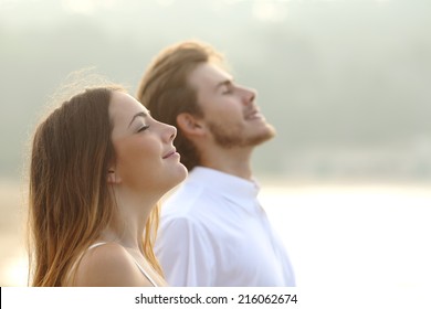 Profile of a couple of man and woman breathing deep fresh air together at sunset               