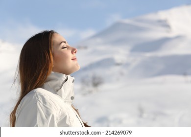 Profile of an explorer woman breathing fresh air in winter with a snowy mountain in the background - Powered by Shutterstock