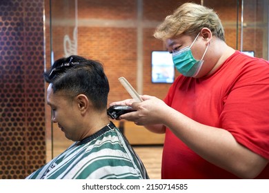 Profile Of A Fat Asian Barber With Mask Cutting The Hair Of A Gay Asian Man