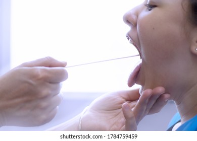 Profile Of A Girl With Hands Of Doctor Using A Tongue Depressor