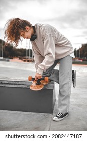 Profile Of Girl Leaning Over Skateboard Adjusting Wheel