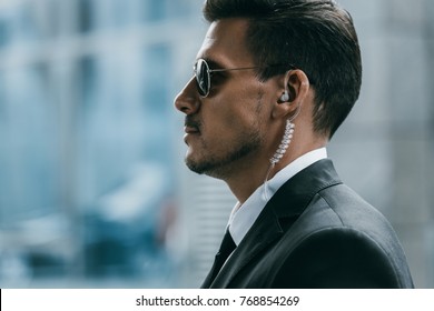 profile of handsome security guard with sunglasses and security earpiece