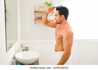 Profile Of A Handsome Strong Man Looking In The Bathroom Mirror Combing His Hair And Using Hair Products After Showering