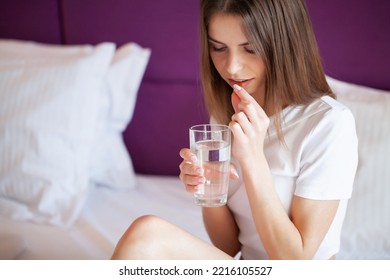 Profile Of Happy Girl Taking Omega 3 Pill On Bed In Morning At Home