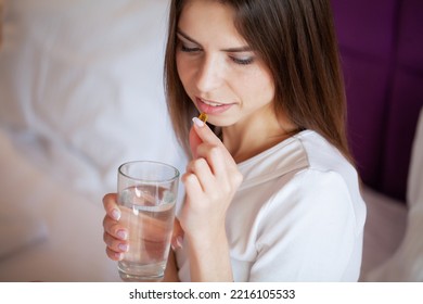 Profile Of Happy Girl Taking Omega 3 Pill On Bed In Morning At Home