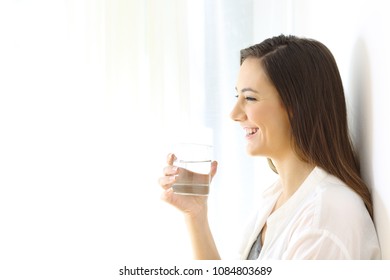 Profile Of A Happy Woman Holding A Glass Of Water Looking Away At Home Isolated On White At Side