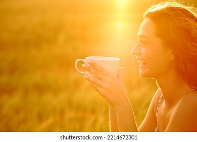 Profile of a happy woman laughing drinking coffee at sunset