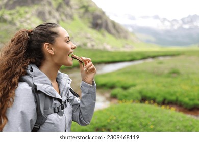 Profile of a hiker eating cereal bar in a valley in the mountain - Powered by Shutterstock