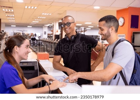 Profile horizontal photo of a smiling receptionist attending two sportive men in a gym