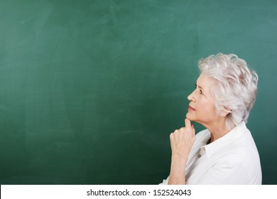 Profile horizontal portrait of a thoughtful senior woman with a blank chalkboard behind