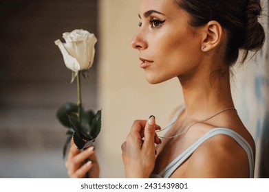 Profile of an innocent ballet dancer holding a white rose in rustic building. A fragile and gracious ballet dancer holding a white rose in abandoned place. Grace against the merciless places. - Powered by Shutterstock