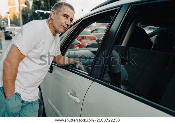 Profile of man in casual summer clothes\
looking out open car window. Travel companion, conversation with\
taxi driver, conflict\
resolution
