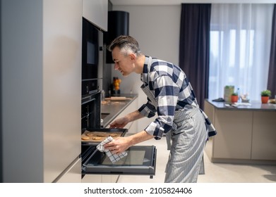 Profile Of Man Putting Baking Sheet In Oven