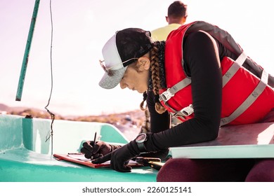 Profile of a marine biologist writing data on top of a boat at sea