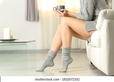 Profile of a perfect woman waxed legs in winter sitting on a sofa in the living room at home