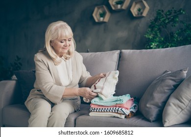 Profile photo of amazing white haired aged granny holding tidy pullover hands put it in stack spring general cleaning house sitting divan living room indoors - Powered by Shutterstock