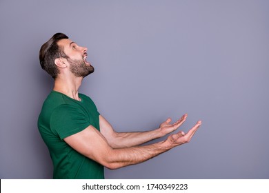 Profile photo of attractive amazed handsome guy good mood raise arms up side empty space waiting novelty product falling catch wear casual green t-shirt isolated grey color background