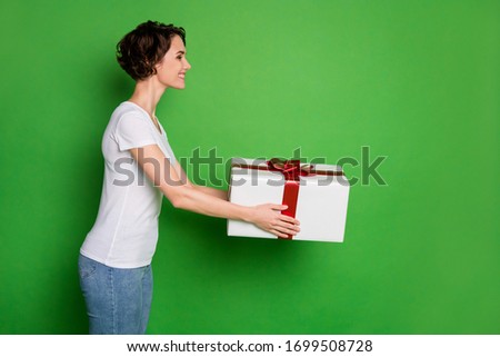 Profile photo of beautiful lady wavy short hairdo hold large giftbox giving taking surprise present secret delivery service courier wear casual t-shirt jeans isolated green color background