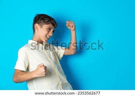 Profile photo of excited Beautiful kid boy wearing casual shirt good mood raise fists screaming rejoicing overjoyed basketball sports fan supporter