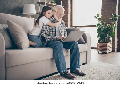 Profile Photo Of Funny Old Grandpa Little Granddaughter Sit Sofa Stay House Quarantine Safety Watch Movie Notebook Talk Skype Relatives Modern Design Interior Living Room Indoors