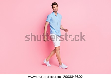 Profile photo of handsome guy walk shiny white smile wear blue shirt shorts shoes isolated on pink color background