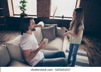 Profile photo of little adorable lady her handsome daddy sit comfy sofa telling secrets communicating drink hot beverage cup spend weekend time domestic house room indoors
