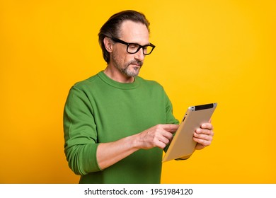 Profile photo of man hold tablet serious look screen typing wear green pullover isolated yellow color background - Powered by Shutterstock