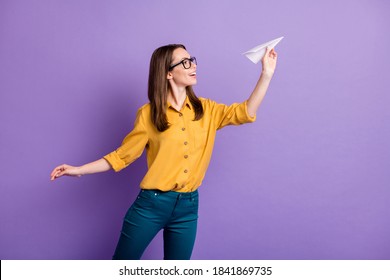 Profile photo of pretty girl hold throwing origami plane wear eyewear yellow shirt blue trousers isolated violet color background