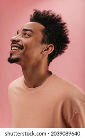  Profile Photo Of Radiant Cute Guy Of Dark Skin With Beard Looks Up At Top, Smiling Broadly. Man On Isolated Room With Good Lighting.