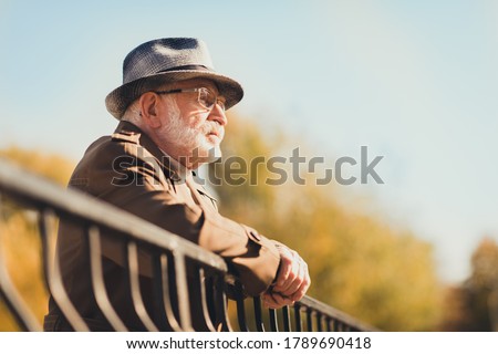 Profile photo of retired old white hair gloomy grandpa street central park walk look frustrated contemplating think past future lean metal fence wear autumn glasses jacket hat outside