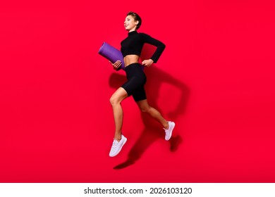 Profile photo of runner cheerful lady jogging carry mat carpet wear black cropped top isolated red color background