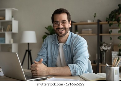 Profile Picture Of Successful Man Worker Employee College University Student Sitting By Work Desk At Home Office Looking At Camera. Portrait Of Motivated Young Guy Studying Working Online Using Laptop