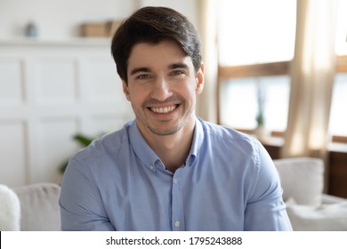 Profile picture of young handsome man sitting on sofa, enjoying talking with friends in social network. Smiling millennial guy job seeker communicating via video call with hr manager from home.