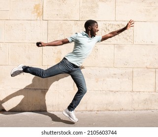 Profile portrait African American man jumping with arms outstretched