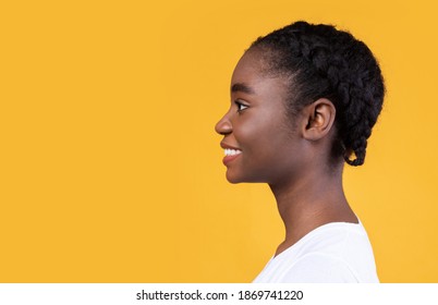 Profile Portrait Of African American Young Woman Smiling Looking Aside At Copy Space Posing Over Yellow Studio Background. Side View, Advertisement With Happy Black Female And Blank Space For Text