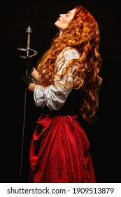 Profile portrait of a beautiful and brave red-haired woman with a battle epee (rapier) on a black background. Historical reconstruction of the 16-17th centuries.