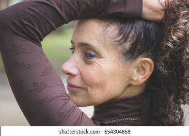 Profile Portrait Of Beautiful Middle Aged Woman Looking Over Her Shoulder With One Hand On Her Hair. Mature Lady Fashion Model, Elegance Concept. Brown Shirt With Flower Pattern