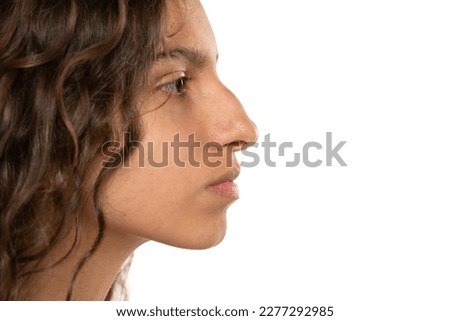 Profile portrait of a beautiful serious young woman, a nose with a hump on white studio background