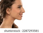 Profile portrait of a beautiful smiling young woman, a nose with a hump on white studio background