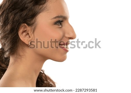Profile portrait of a beautiful smiling young woman, a nose with a hump on white studio background